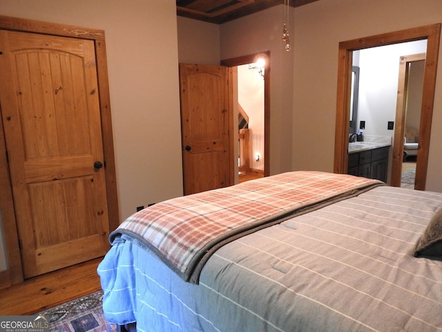 bedroom with ensuite bath and wood finished floors