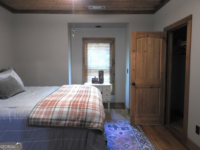 bedroom with visible vents, wood finished floors, and baseboards