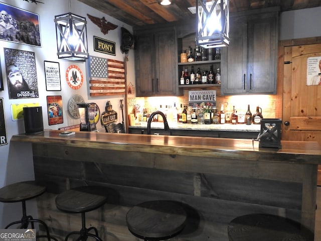 bar featuring a sink, a bar, decorative light fixtures, wooden ceiling, and tasteful backsplash