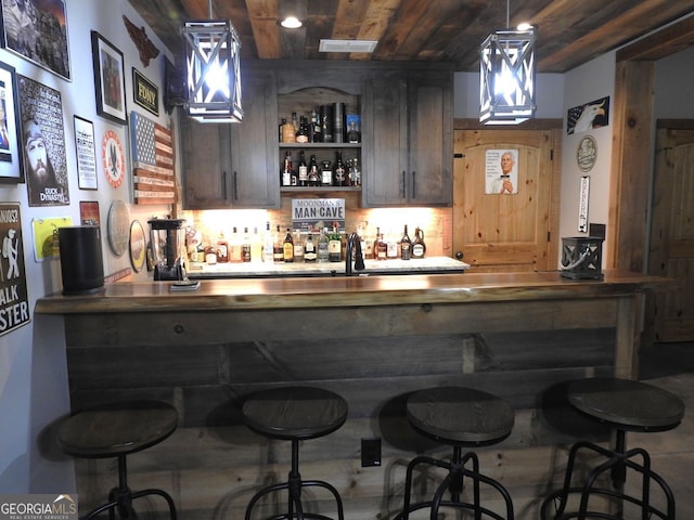 bar featuring a sink, backsplash, bar, decorative light fixtures, and wooden ceiling