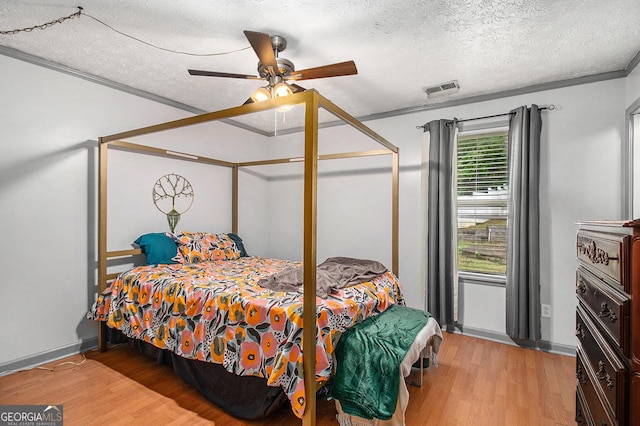 7845 Chase Woods Dr, Jonesboro, GA 30236 - bedroom with light wood-type flooring, crown molding, a textured ceiling, a ceiling fan, and baseboards