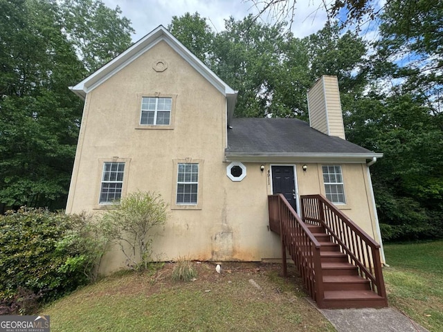 view of front of home featuring a shingled roof, stucco siding, and a chimney