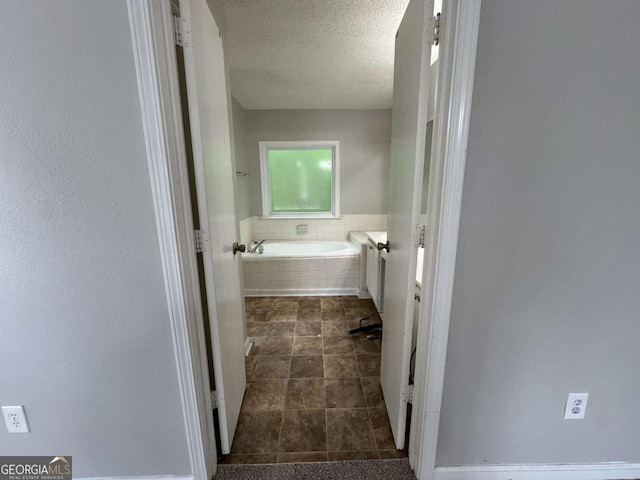 bathroom with a garden tub, a textured ceiling, and tile patterned flooring