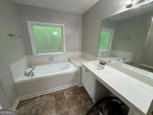 full bathroom featuring a textured ceiling, vanity, and a bath