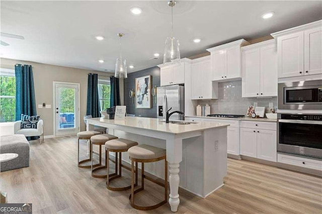 kitchen with a wealth of natural light, a sink, a kitchen breakfast bar, stainless steel appliances, and a kitchen island with sink