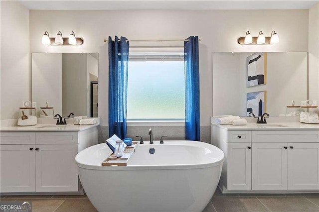 bathroom with a sink, a freestanding bath, two vanities, and tile patterned floors