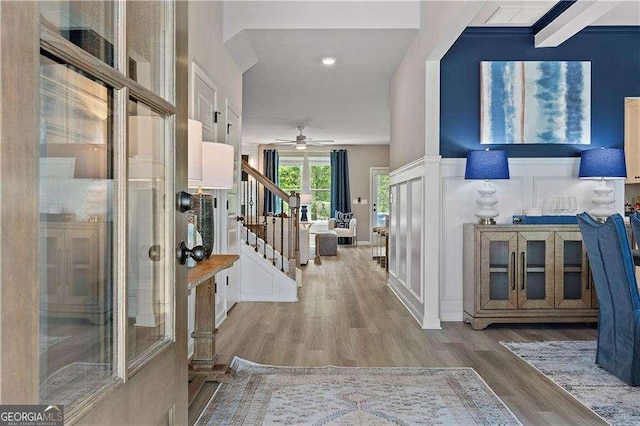 foyer with stairs, a ceiling fan, and wood finished floors