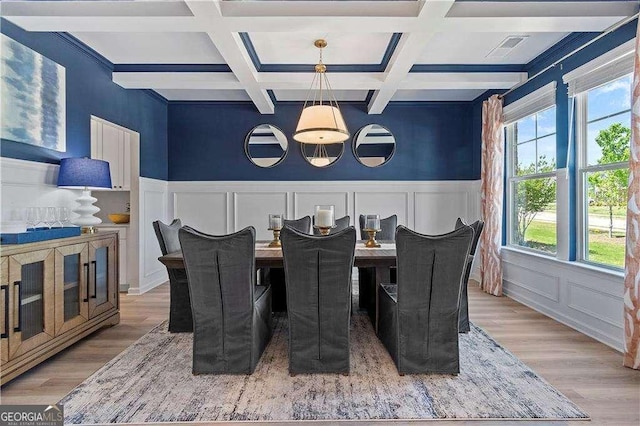 dining room with a decorative wall, coffered ceiling, wood finished floors, and beamed ceiling