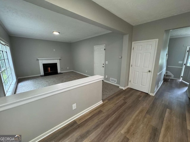unfurnished living room featuring visible vents, baseboards, and dark wood-style floors