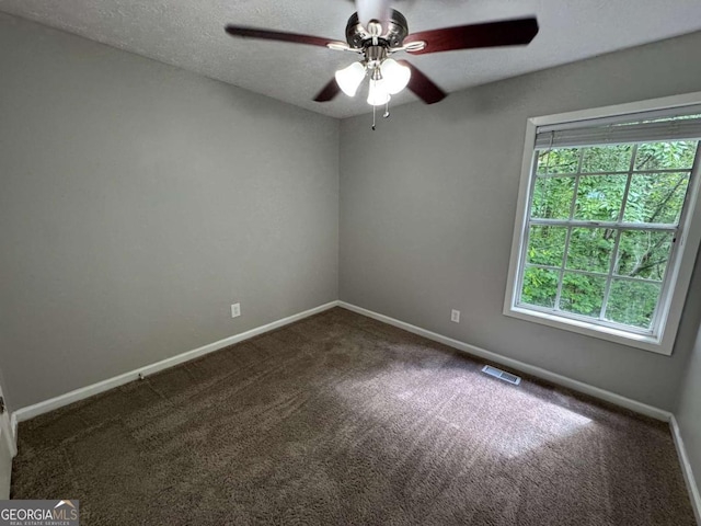 carpeted spare room featuring baseboards, visible vents, and ceiling fan
