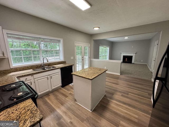 kitchen with a sink, black appliances, dark wood finished floors, white cabinets, and a kitchen island