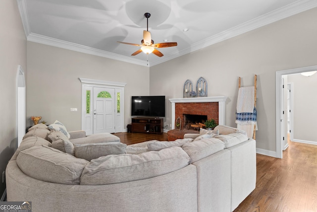 living room featuring a ceiling fan, baseboards, crown molding, and wood finished floors
