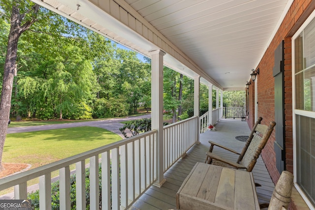 wooden terrace featuring a porch and a yard