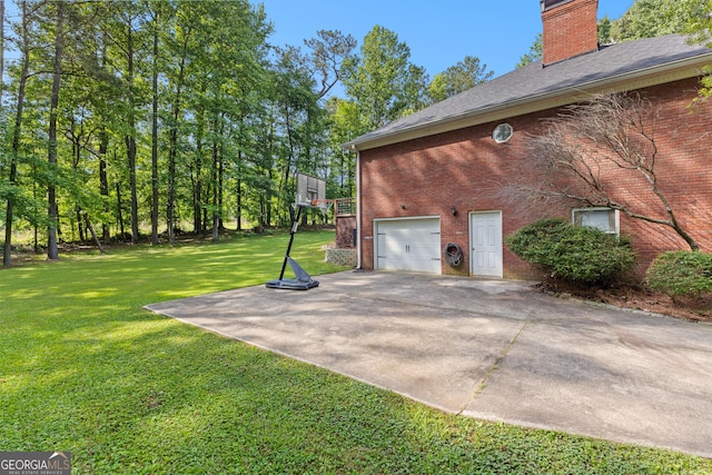 view of side of home with a garage, a chimney, a lawn, brick siding, and driveway