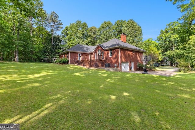 rear view of house featuring a lawn, brick siding, and an attached garage
