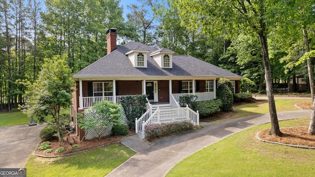 view of front of property with a porch, a shingled roof, a front lawn, and a chimney