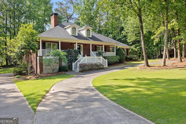 view of front of home featuring covered porch, a chimney, a front yard, brick siding, and driveway