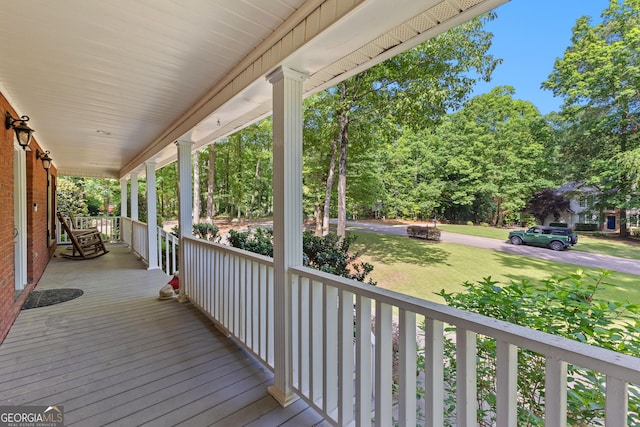 deck featuring covered porch and a lawn