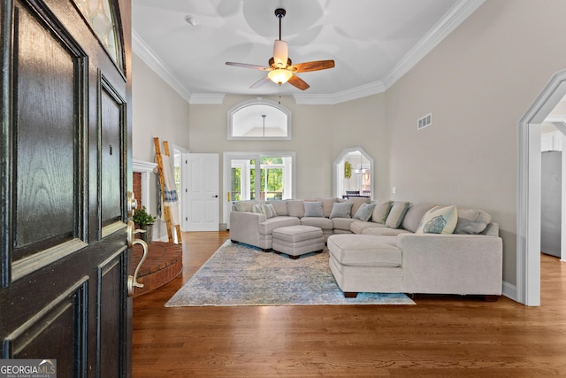 living area with crown molding, dark wood-style flooring, ceiling fan, and visible vents