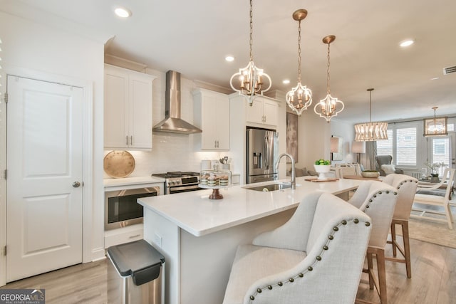 3313 Bartee Walk, Suwanee, GA 30024 - kitchen featuring a sink, stainless steel appliances, light wood-type flooring, wall chimney exhaust hood, and an inviting chandelier