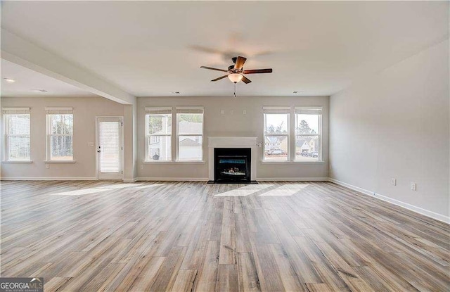 512 Dolce Rd, Locust Grove, GA 30248 - unfurnished living room with wood finished floors, baseboards, a ceiling fan, and a fireplace with flush hearth