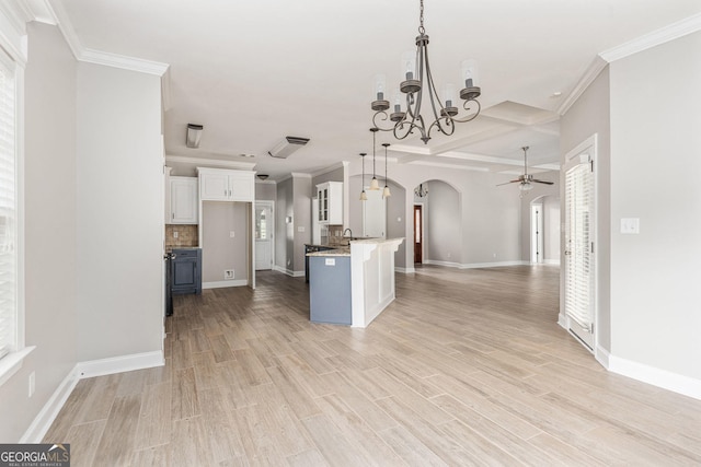 kitchen featuring light wood finished floors, ceiling fan with notable chandelier, open floor plan, white cabinetry, and arched walkways