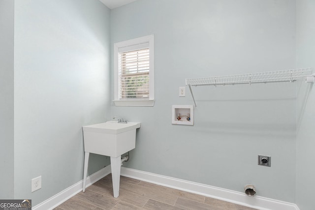laundry area featuring laundry area, hookup for an electric dryer, washer hookup, baseboards, and light wood-style floors