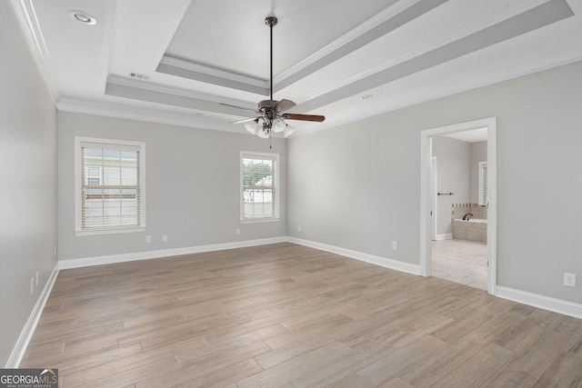 unfurnished bedroom featuring visible vents, crown molding, light wood finished floors, a tray ceiling, and baseboards