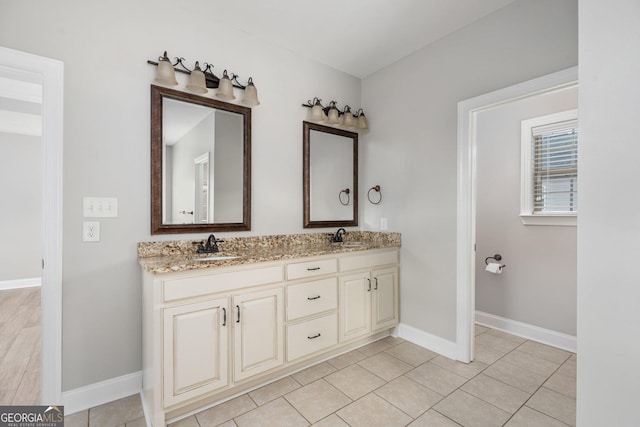 full bathroom with a sink, double vanity, baseboards, and tile patterned flooring