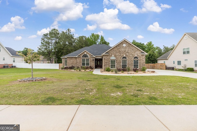 view of front of home with brick siding, fence, a front yard, and central AC