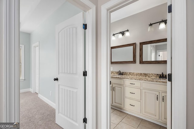 full bathroom with double vanity, baseboards, and a sink