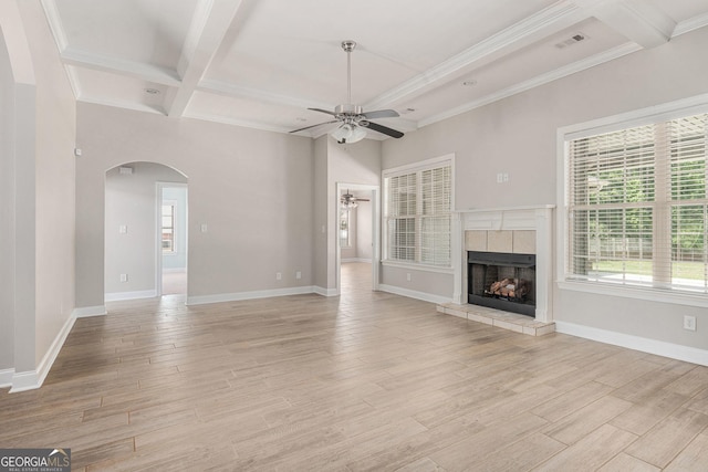 unfurnished living room featuring coffered ceiling, a wealth of natural light, ceiling fan, visible vents, and arched walkways