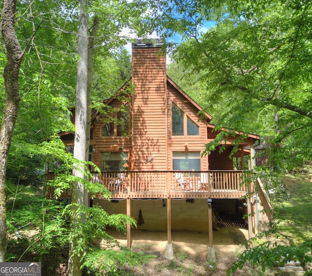 rear view of property with a chimney and a wooden deck