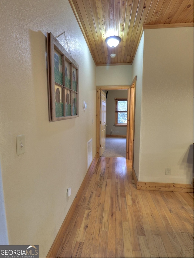 corridor featuring wooden ceiling, visible vents, baseboards, and light wood-style floors