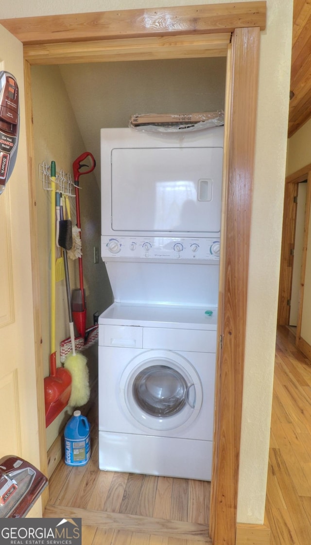 washroom featuring laundry area, stacked washer / dryer, and wood finished floors
