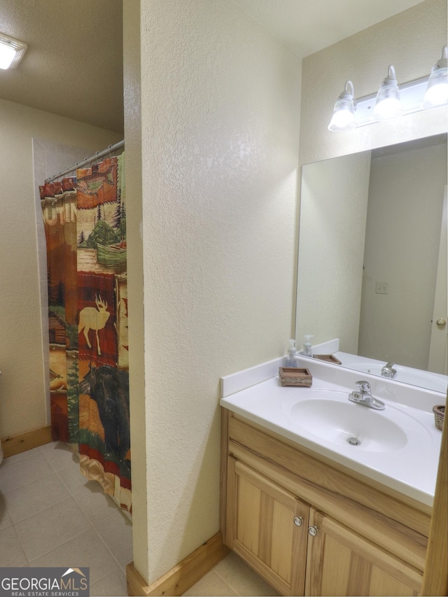 bathroom featuring baseboards, a shower with shower curtain, tile patterned floors, vanity, and a textured wall