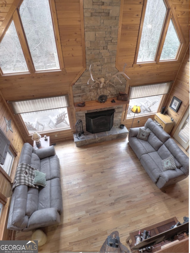 living area with a towering ceiling, wooden walls, and wood finished floors