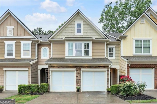 multi unit property featuring roof with shingles, driveway, an attached garage, and board and batten siding
