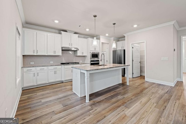 kitchen featuring stainless steel appliances, white cabinets, under cabinet range hood, decorative backsplash, and ornamental molding