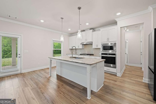 kitchen featuring under cabinet range hood, ornamental molding, a sink, a center island with sink, and stainless steel appliances