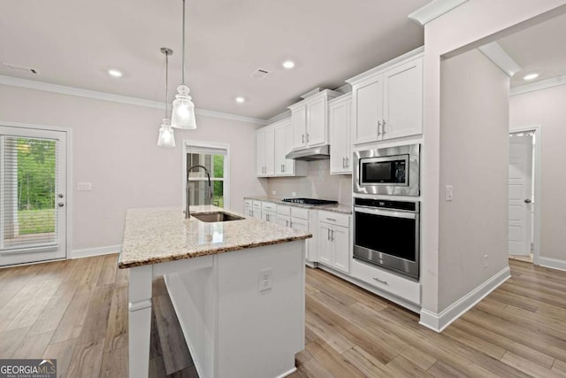 kitchen with under cabinet range hood, ornamental molding, a sink, white cabinetry, and stainless steel appliances
