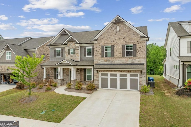 craftsman house with stone siding, concrete driveway, and a front lawn