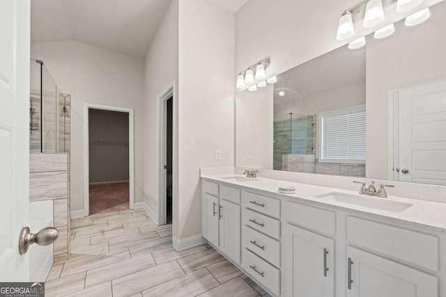 bathroom with a stall shower, lofted ceiling, double vanity, and a sink