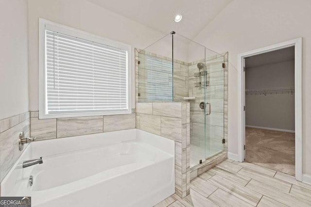 full bathroom with a walk in closet, a garden tub, baseboards, and a stall shower