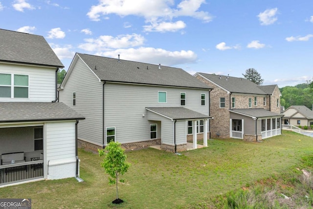 rear view of house with a sunroom, a residential view, and a lawn