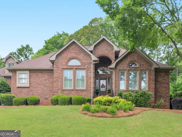 view of front of house featuring roof with shingles, brick siding, and a front lawn