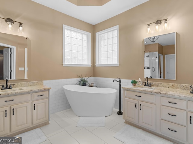 bathroom featuring a shower stall, tile walls, a freestanding bath, and a sink
