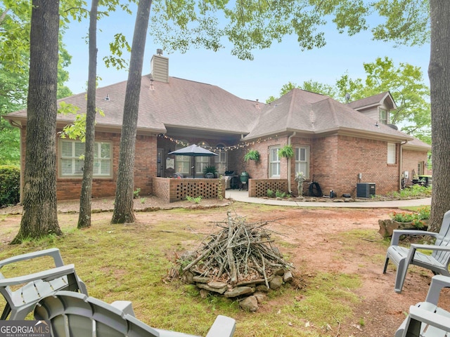 back of property featuring a chimney, central AC, and brick siding