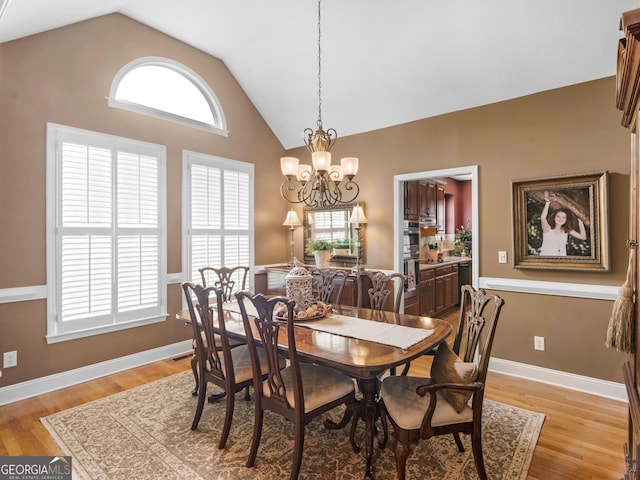 dining space featuring a chandelier, light wood-style floors, vaulted ceiling, and baseboards