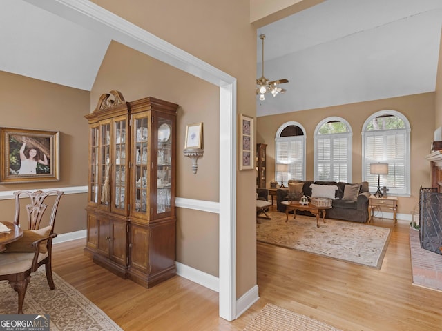 interior space with baseboards, a notable chandelier, light wood finished floors, and high vaulted ceiling